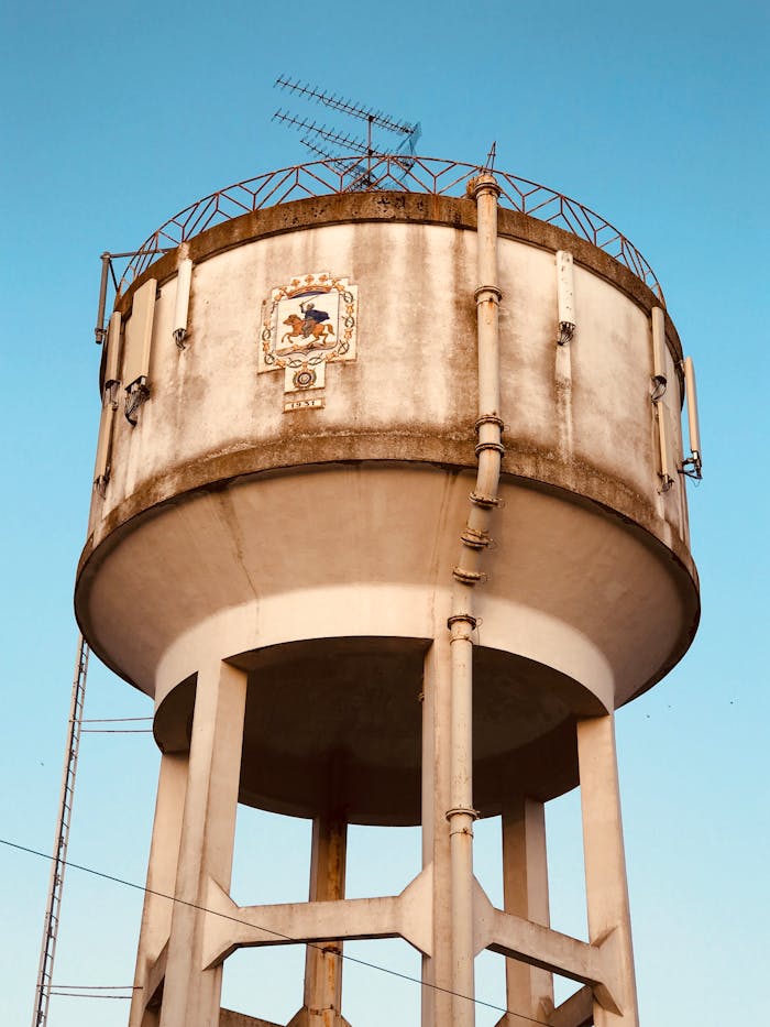 Large concrete water tower with antennas, captured on a clear day.