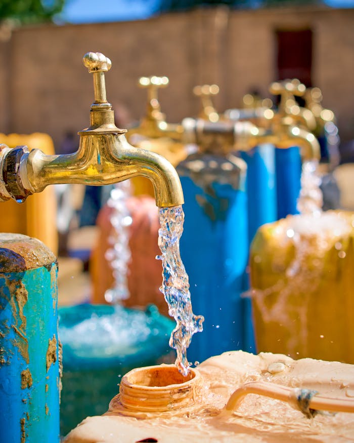 Outdoor array of colorful water taps with flowing streams in daylight.