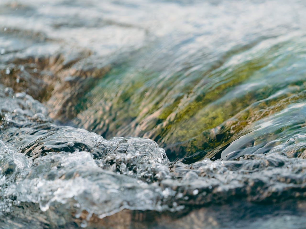 A detailed shot of flowing clear water with a greenish hue, showcasing nature's beauty.